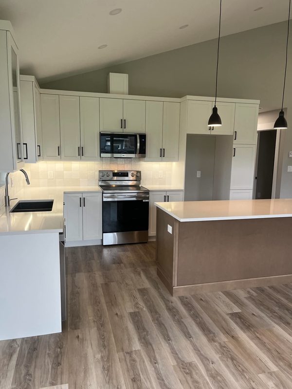 A kitchen with a vaulted ceiling, cream shaker cabinets and a wood-based island